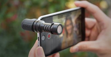 Manos sosteniendo un teléfono que tiene un microfono conectado